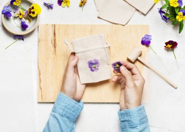 Dördüncü adım. Parmak izini ortaya çıkarmak ve çiçeği koparmak için üst kumaş katmanını soy. Kumaş torbada çekiçli çiçek izleri. Çocuk konsepti için doğal malzeme. Üst görünüm.