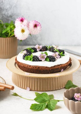 Vanilya kremalı, böğürtlenli, çiçekli ve limon yapraklı ev yapımı çikolatalı pasta. Lezzetli tatlı konsept. Seçici odaklanma. Boşluğu kopyala.