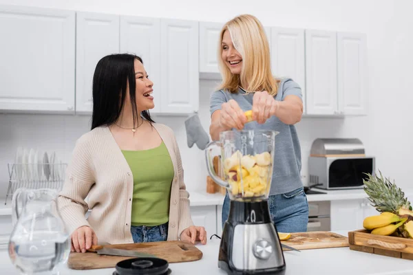 stock image Cheerful multiethnic friends talking while preparing smoothie in kitchen 