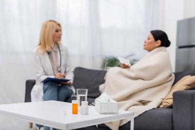 Evde bulanık doktor ve Asyalı hastaların yanında haplar ve peçeteler. 