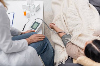 Doktor evdeki koltukta bulanık hastada tonometre kullanıyor. 