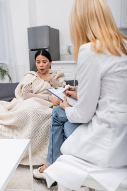 Hasta Asyalı bir hastanın evinde öksürürken panoya yazı yazan doktor. 