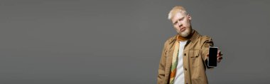 Sakallı albino ceketli adam elinde gri pankartta izole edilmiş akıllı telefon tutuyor. 