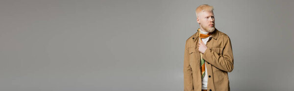 bearded albino man in stylish shirt jacket and silk scarf posing isolated on grey, banner