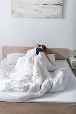 Passionate man kissing girlfriend on bed at home 