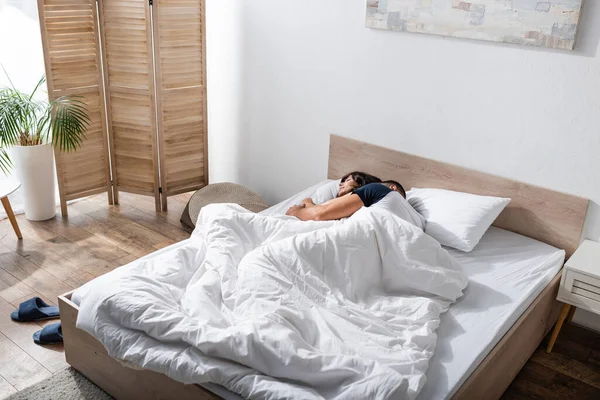 Man hugging girlfriend on bed in morning 