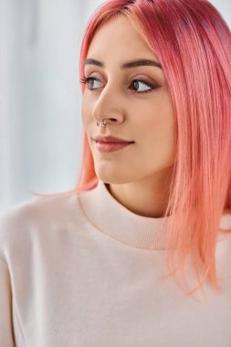 Çekici, neşeli, pembe renkli saçları olan beyaz kazaklı, poz veren ve başka yöne bakan bir kadın.