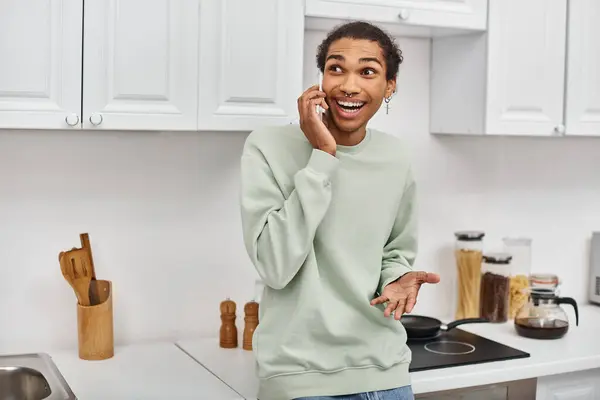 stock image appealing cheerful african american man in white cozy sweater talking by phone and looking away