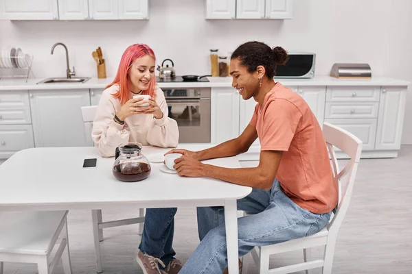 コーヒーと一緒にテーブルに座って お互いを見ている良い見て陽気な多様なカップル ロイヤリティフリーのストック画像