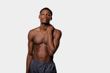 Güçlü Afrikalı Amerikalı bir adam, bir stüdyoda kendine güvenen bir poz veriyor. Beyaz bir arka planı var..