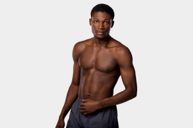 Shirtless African American man stands confidently against a stark white backdrop. clipart