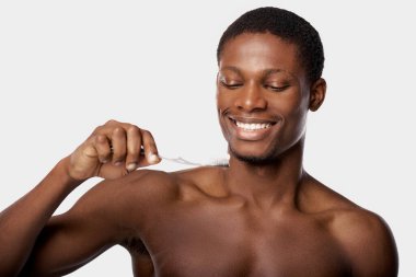 Stüdyoda dişlerini diş fırçasıyla beyaz arka planda fırçalayan Afro-Amerikan bir adam..