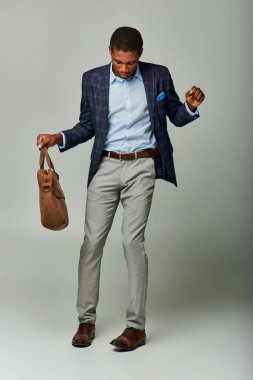 Kareli ceketli bir Afro-Amerikalı işadamı bir çanta tutuyor, iş yerinde bir güne hazır..