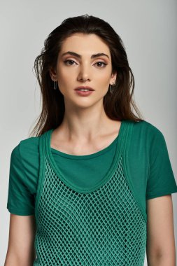 A young woman in a green mesh top and t-shirt looks directly at the camera. clipart