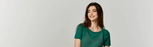 stock image A young woman in a green dress smiles as she looks to the side.