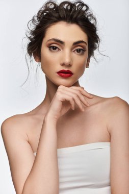 Beyaz bluzlu, kırmızı rujlu, elleri çenesinde genç esmer..