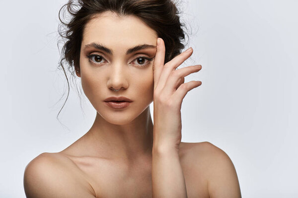 Элегантная молодая женщина смотрит в камеру, лаская щеку.