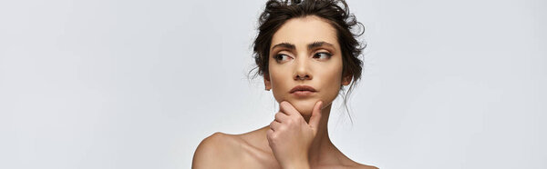 Красивая молодая женщина в элегантной одежде, потерявшаяся в мыслях с подбородком в руке.