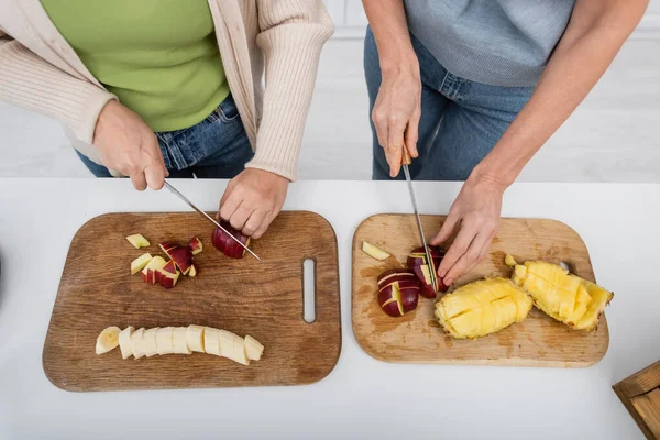 Top view of friends cutting fresh fruits on cutting boards in kitchen — Stock Photo