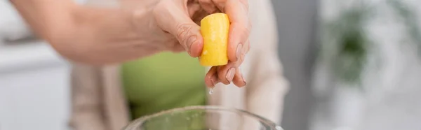 Ausgeschnittene Ansicht einer Frau, die Zitrone über dem Mixer in der Küche auspresst, Banner — Stockfoto