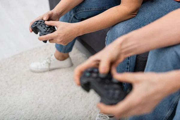 KYIV, UCRANIA - 2 de diciembre de 2021: Vista recortada de una mujer jugando un videojuego con una amiga madura borrosa en casa — Stock Photo