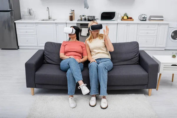 Women in vr headsets sitting on couch while gaming at home — Stock Photo