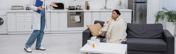 Ill asian woman looking at doctor with clipboard at home, banner — Stock Photo