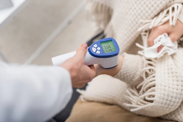 Cropped view of doctor measuring temperature of blurred patient at home — Stock Photo
