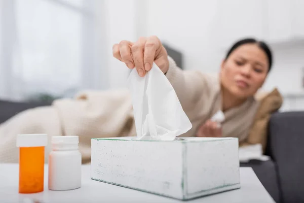 Blurred sick woman taking napkin near pills at home — Stock Photo