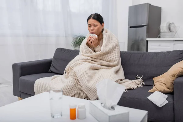 Fatigué et malade asiatique femme tenant serviette près floue pilules à la maison — Photo de stock