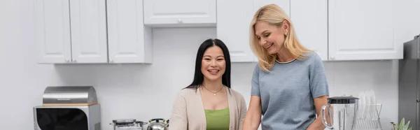 Cheerful interracial friends standing in kitchen, banner — Stock Photo
