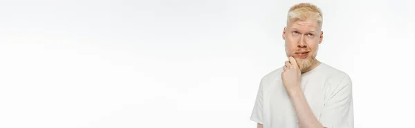 Pensive albino man in t-shirt touching beard while thinking on white, banner — Stock Photo