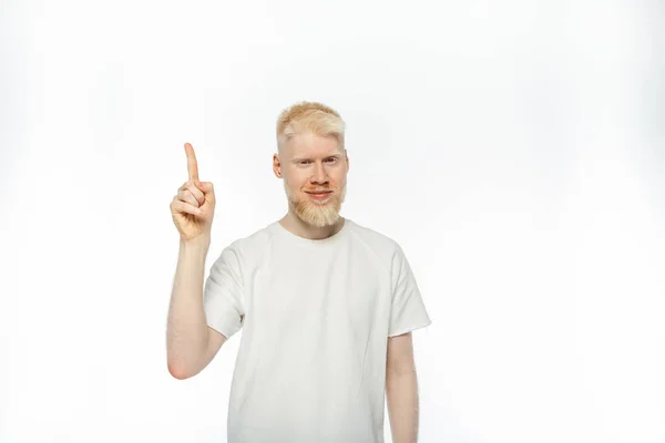 Bearded albino man in t-shirt smiling while showing idea gesture on white background — Stock Photo