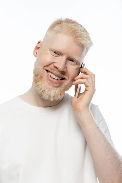 Felice uomo albino in t-shirt che parla su smartphone e sorride isolato sul bianco — Foto stock