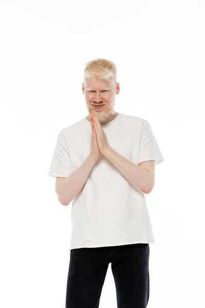 Cheerful albino man in t-shirt standing with praying hands isolated on white — Stock Photo