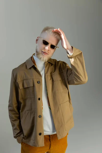 Uomo albino sorridente in eleganti occhiali da sole e camicia giacca isolata su grigio — Foto stock