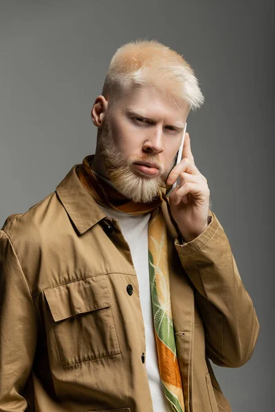 Bearded albino man in shirt jacket having phone call on smartphone isolated on grey — Stock Photo