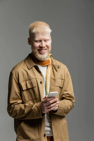 Allegro uomo albino in giacca elegante camicia e sciarpa di seta messaggistica smartphone isolato su grigio — Foto stock