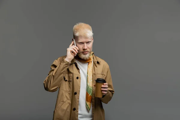 Barbuto albino uomo in camicia giacca tenendo tazza di carta e parlando su smartphone isolato su grigio — Foto stock