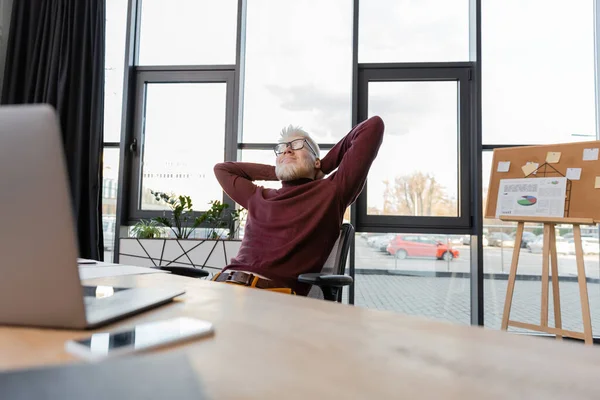 Pleased albino businessman in glasses resting near gadgets on blurred foreground — Stock Photo