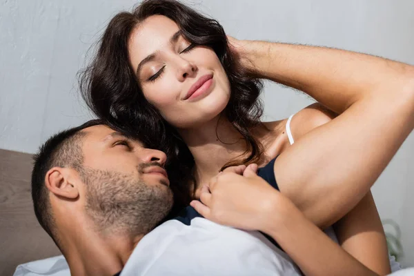 Junger Mann berührt brünette Freundin im Schlafzimmer — Stockfoto