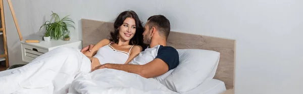 Молодой человек разговаривает с позитивной девушкой на кровати, баннер — Stock Photo