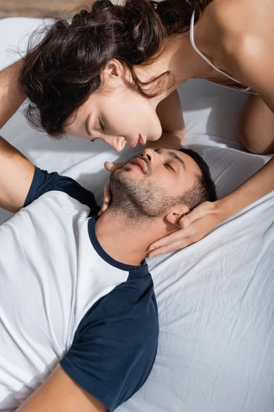 Високий кут зору сексуальна жінка торкається хлопця в піжамі на ліжку — стокове фото