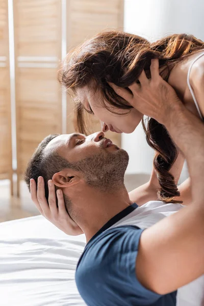 Passionate man kissing brunette girlfriend on bed in morning — Photo de stock