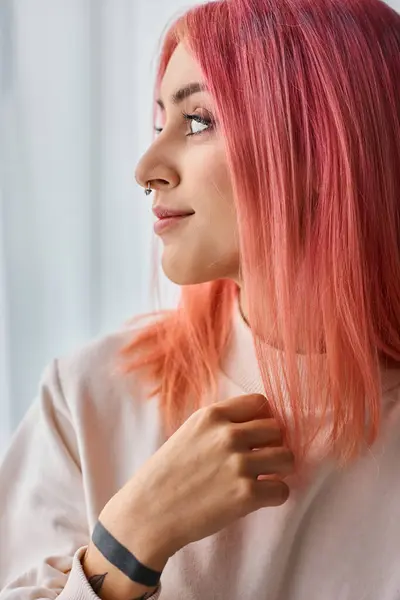 Belle jeune femme joyeuse en pull blanc avec des cheveux vifs roses posant dans la cuisine et regardant loin — Photo de stock