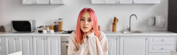 Attraktive junge Frau mit rosafarbenen Haaren in bequemer Homewear schaut in die Kamera, während sie zu Hause in der Küche steht — Stockfoto