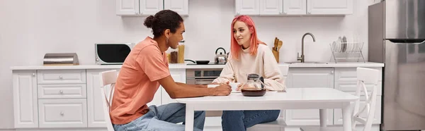 Young multiracial jolly couple spending time together at home and smiling at each other, banner — Stock Photo