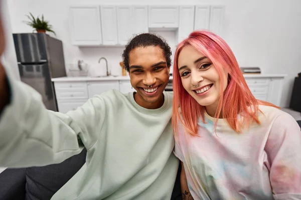 Joyeux couple multiculturel attrayant en tenue décontractée prendre des selfies et sourire à la caméra — Photo de stock