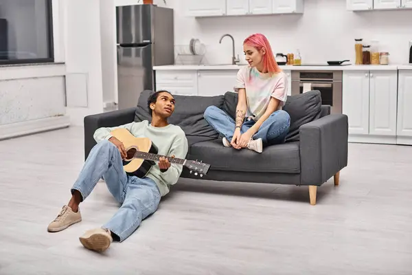 Schöner afrikanisch-amerikanischer Mann spielt Gitarre und schaut seine rosafarbene Freundin liebevoll an — Stockfoto