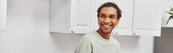 Good looking cheerful african american man in green sweater looking away while in kitchen, banner — Stock Photo